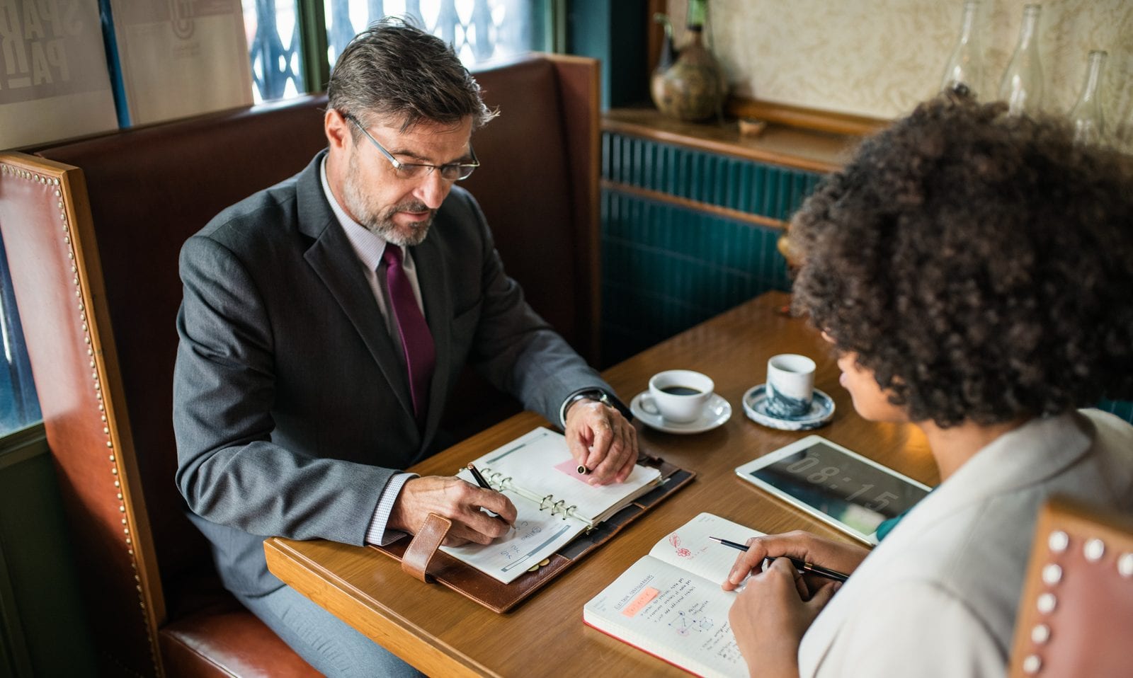 Two colleagues working through notes together across a table